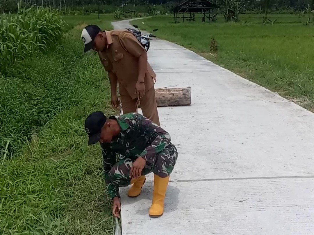 Anggota Satuan Tugas (Satgas) TMMD, Sertu Farid, bersama Kepala Dusun Sukomaju, Desa Lebakharjo, Kecamatan Ampelgading, meninjau langsung hasil pekerjaan jalan rabat beton yang telah selesai 100 persen.